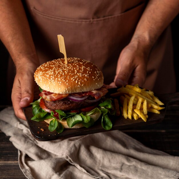 ハンバーガーとフライドポテトとトレイを保持している高角度の男