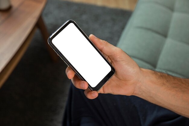 High angle of man at home holding smartphone