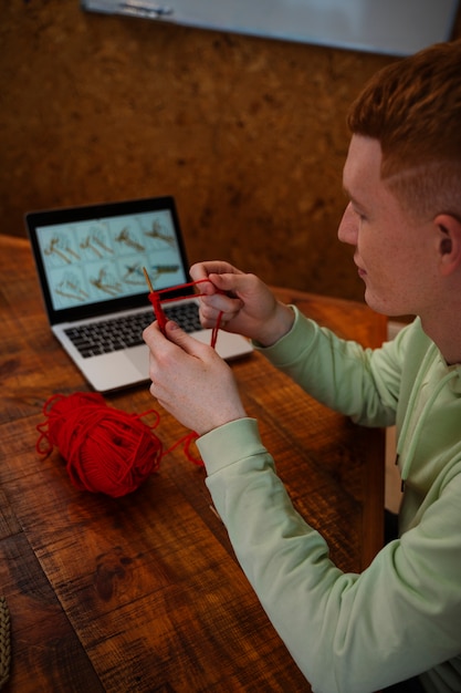 Free photo high angle man knitting at home