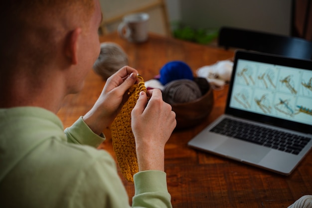 Foto gratuita uomo di alto angolo che lavora a maglia a casa