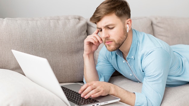 High angle man laid on couch with laptop