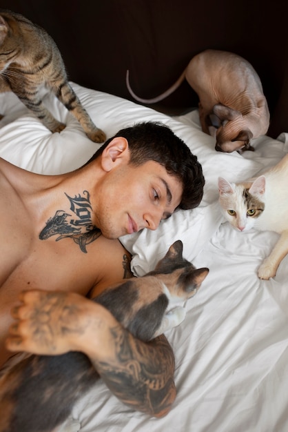 Мужчина под высоким углом лежит в постели с кошками
