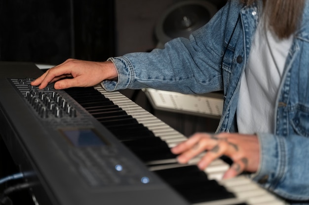 Foto gratuita uomo dell'angolo alto che suona il pianoforte in studio