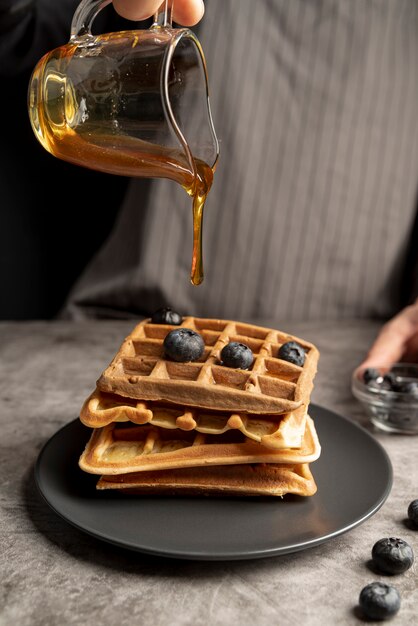 High angle of man pouring syrup of stack of waffles