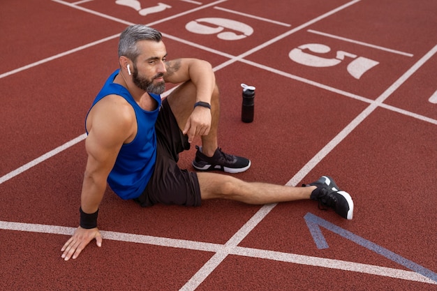 Free photo high angle man sitting on running track