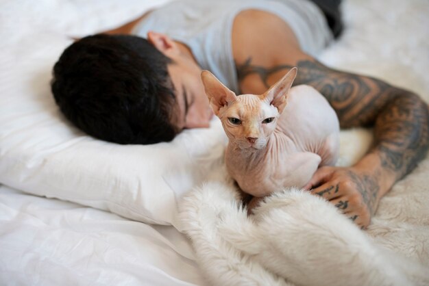 High angle man sleeping in bed with cat