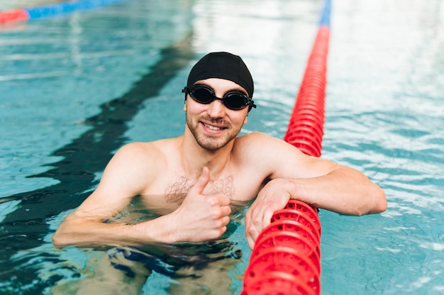 Uomo dell'angolo alto nella piscina che mostra segno giusto