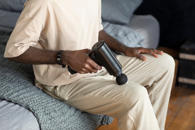 High angle man using massage gun on knee