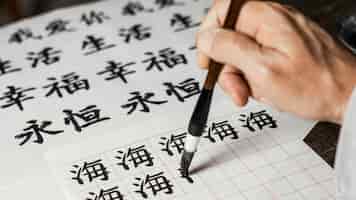 Foto gratuita uomo di alto angolo che scrive simboli cinesi su carta bianca