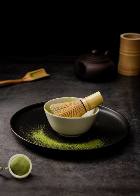 High angle of matcha tea powder in bowl with sieve and plate