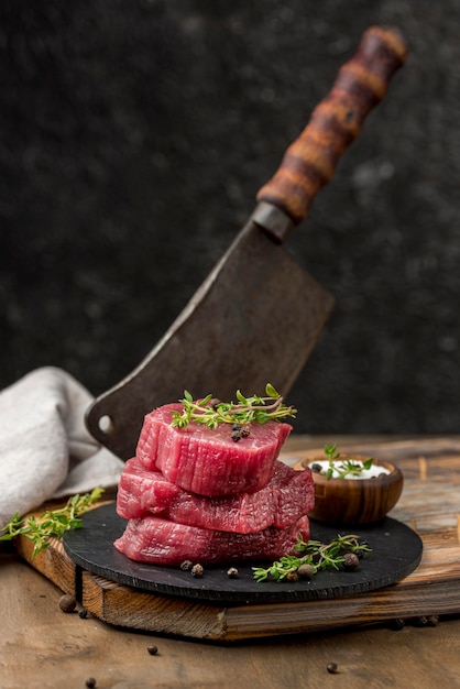 High angle of meat on slate with herbs and cleaver