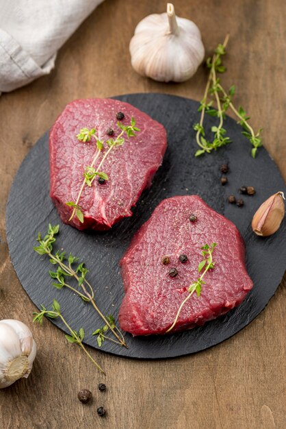 High angle of meat on slate with herbs and garlic