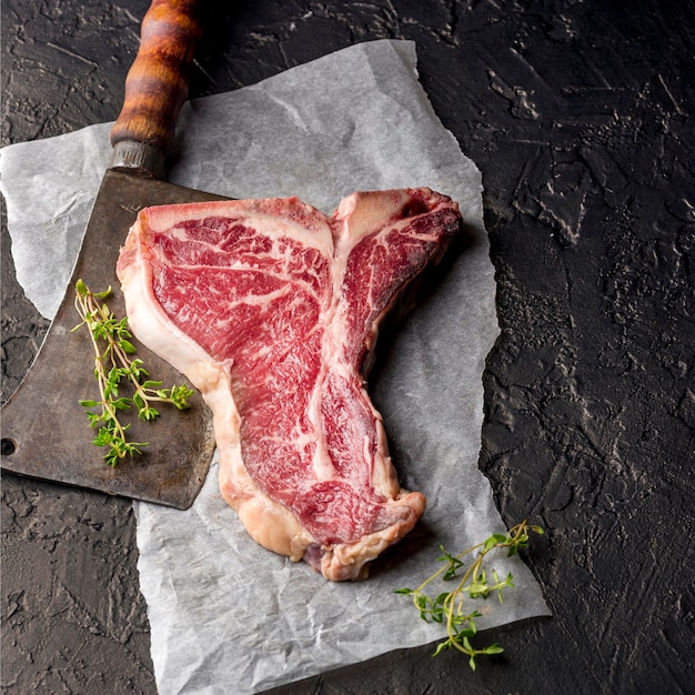 High angle of meat with herbs and cleaver