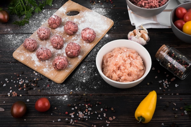 High angle meatballs on wooden board and minced meat