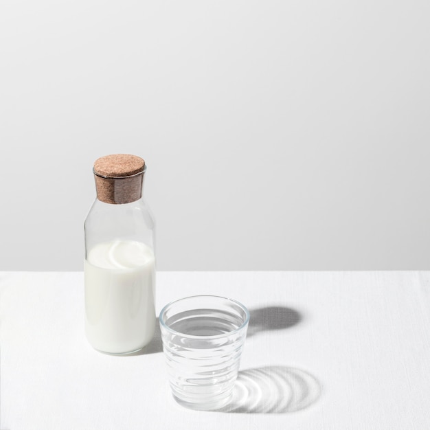 Высокий угол молочной бутылки с пустым стаканом