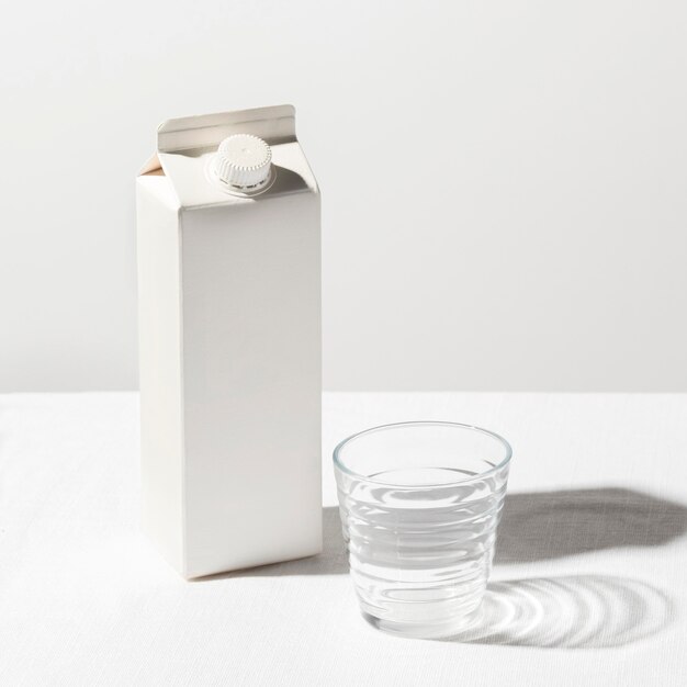 Высокий угол упаковки молока с пустым стаканом