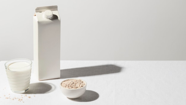 High angle of milk carton with full glass and bowl of oatmeal