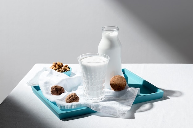 Free photo high angle of milk glass and bottle with walnuts