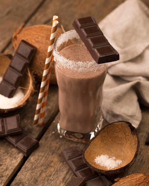 Стакан для молочного коктейля под высоким углом на подносе с шоколадно-кокосовой стружкой