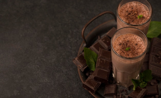 High angle of milkshake glasses on tray with chocolate and copy space