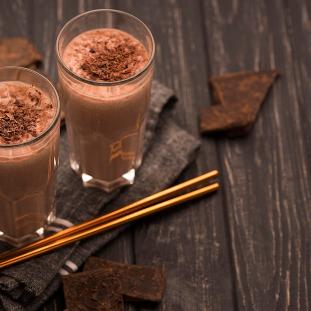 High angle of milkshake glasses with straws and chocolate