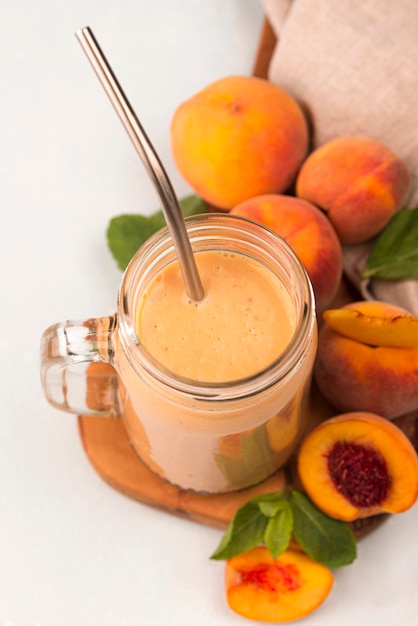 High angle of milkshake with peaches and metal straw