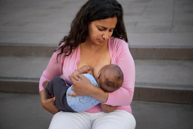 Foto gratuita madre ad alto angolo che allatta al seno all'aperto