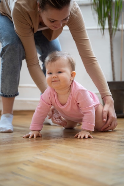 High angle mother helping baby crawl