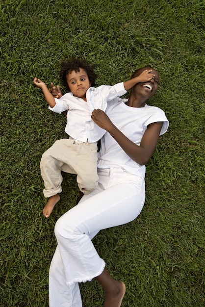 Free photo high angle mother and kid laying on grass