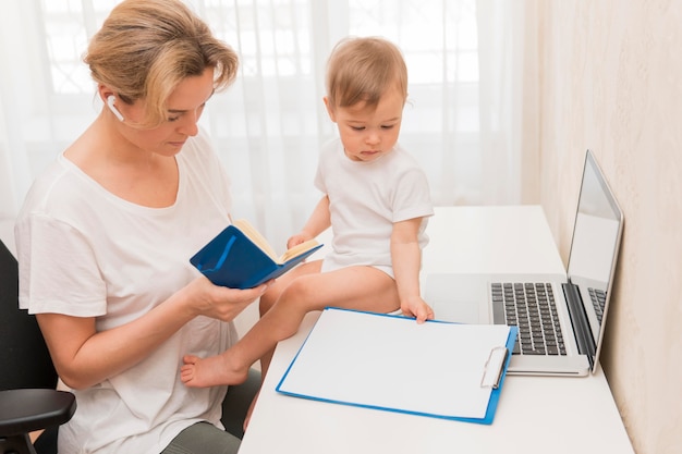 Free photo high angle mother looking in agenda and baby on desk