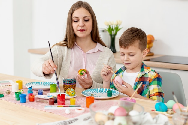 High angle mother and son concentrated to paint eggs