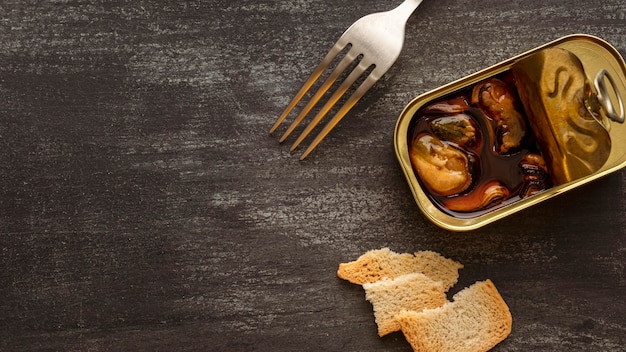 Free photo high angle mussels tin can with toast and fork with copy-space