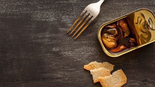 High angle mussels tin can with toast and fork with copy-space