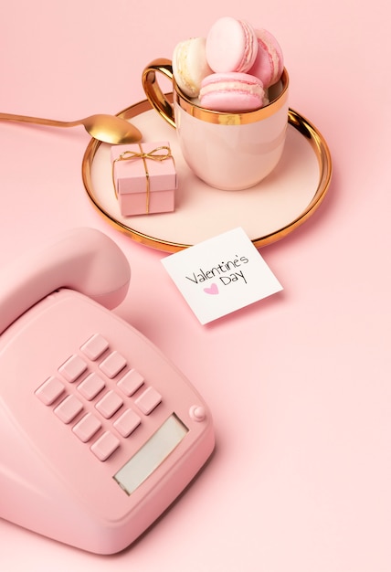 핑크 전화와 발렌타인 데이를 위한 황금 컵에 마카롱의 높은 각도