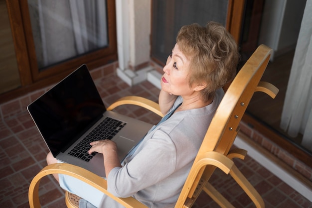 Foto gratuita donna anziana di alto angolo con il computer portatile