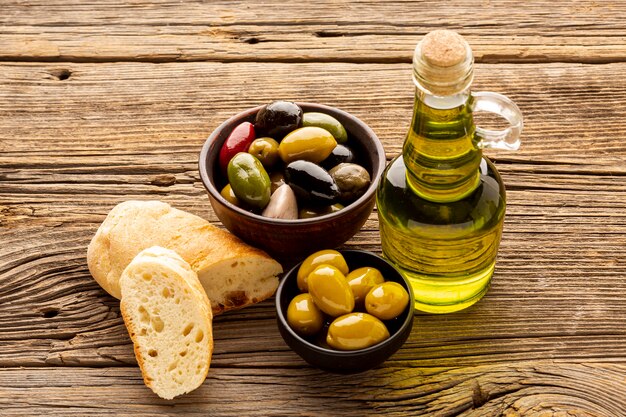 High angle olive bowls bread slices and oil bottles