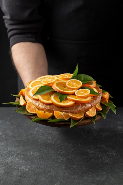 High angle of orange cake held by pastry chef