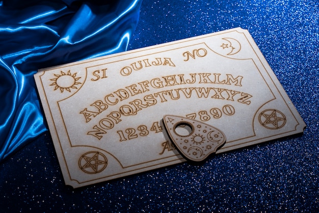 Free photo high angle ouija board and blue silk cloth