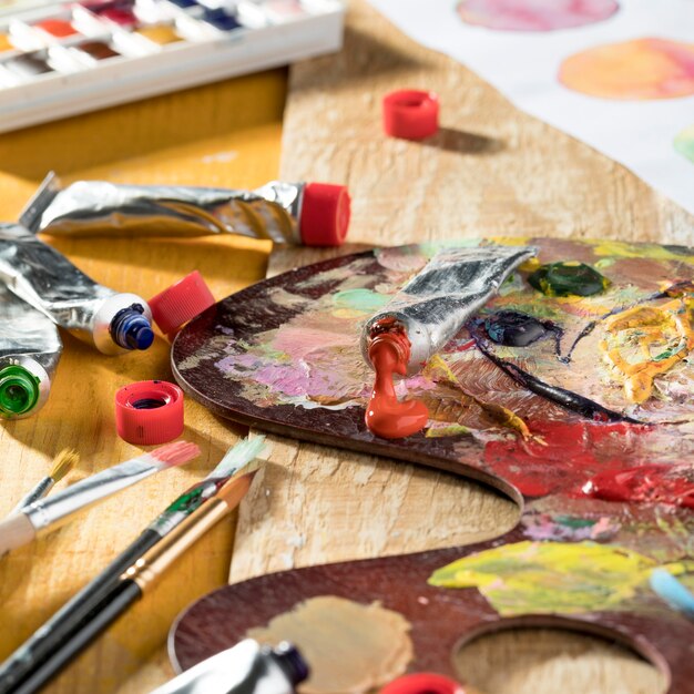 High angle of painting palette with colorful paint and brushes