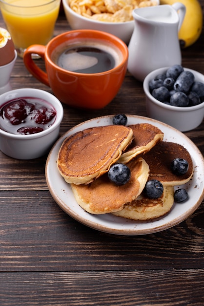 High angle of pancakes for breakfast on plate with blueberries and coffee