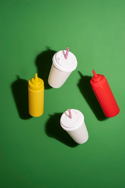 High angle paper cups and sauce bottles