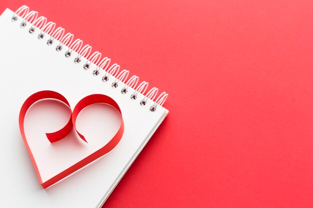 High angle of paper heart shape on notebook with copy space