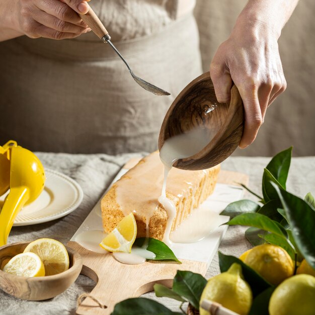 High angle of pastry chef adding topping to lemon cake