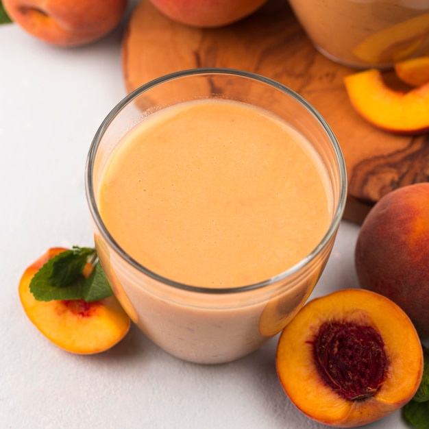 High angle of peach milkshake glass with fruit