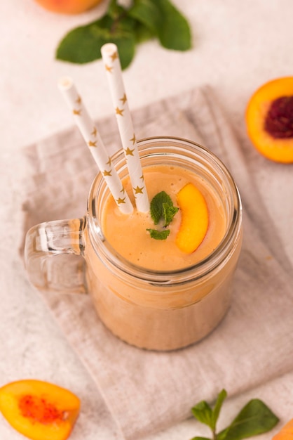 High angle of peach milkshake mug with straws and mint