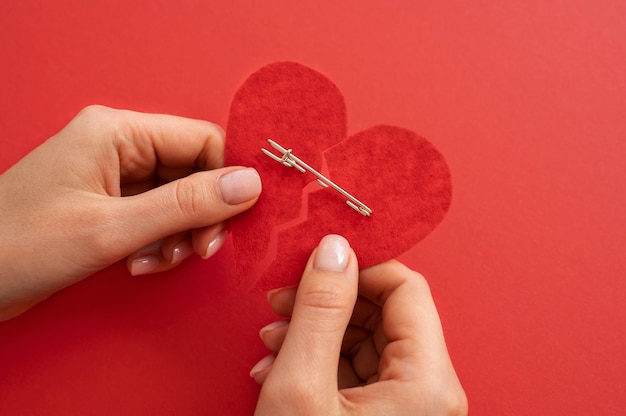 High angle of person holding broken heart put back together with safety pin