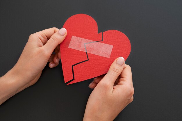 High angle of person holding broken heart put back together with scotch tape