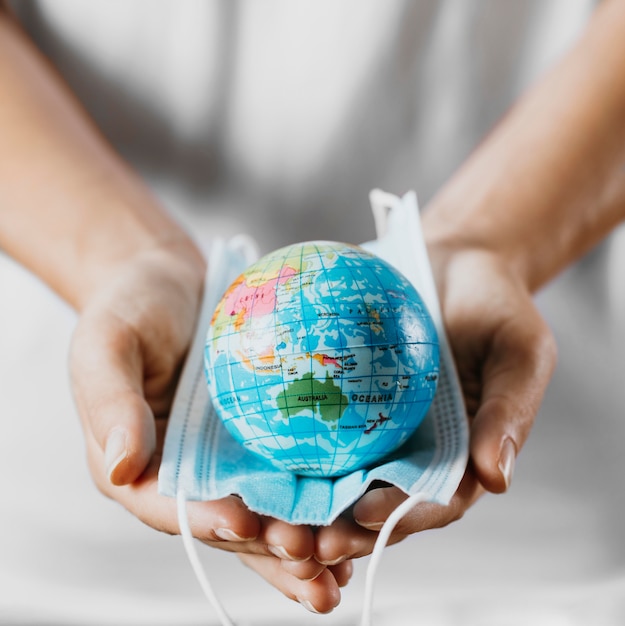 High angle of person holding medical mask with earth globe