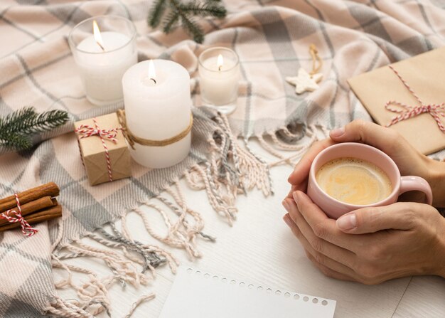 High angle of person holding mug with blanket and candles