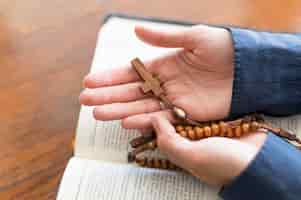 Free photo high angle of person holding rosary with holy book open